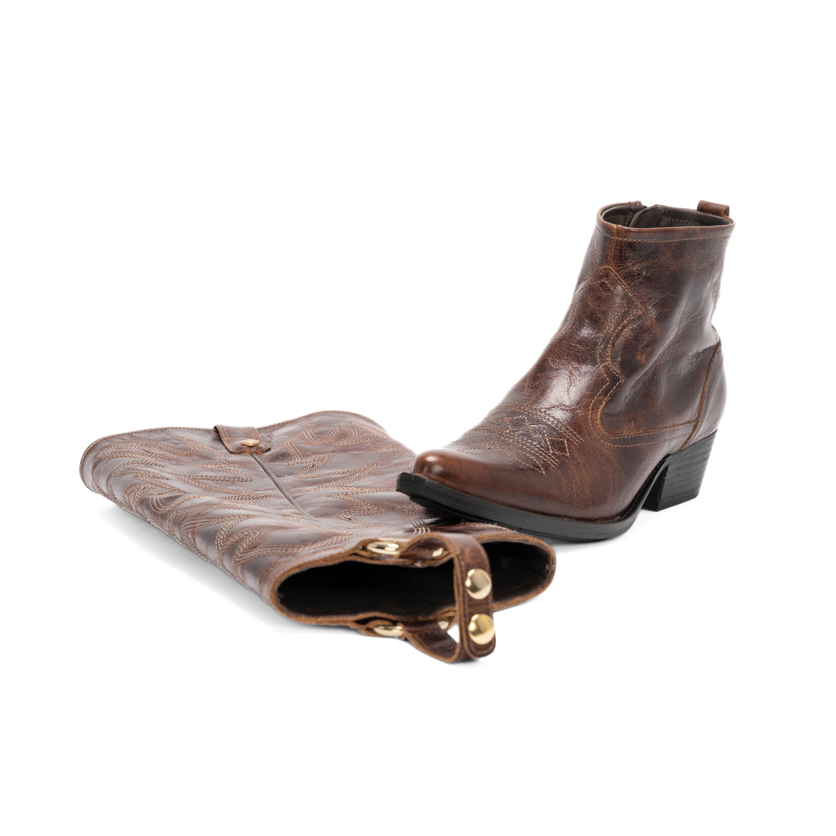 Scarlett Chase Mahogany leather Fiona cowboy bootie with decorative stitching and a side zipper and interchangeable knee-high gaiter with decorative stitching and clip-on straps | 3/4 view of one boot resting on gaiter on a white background