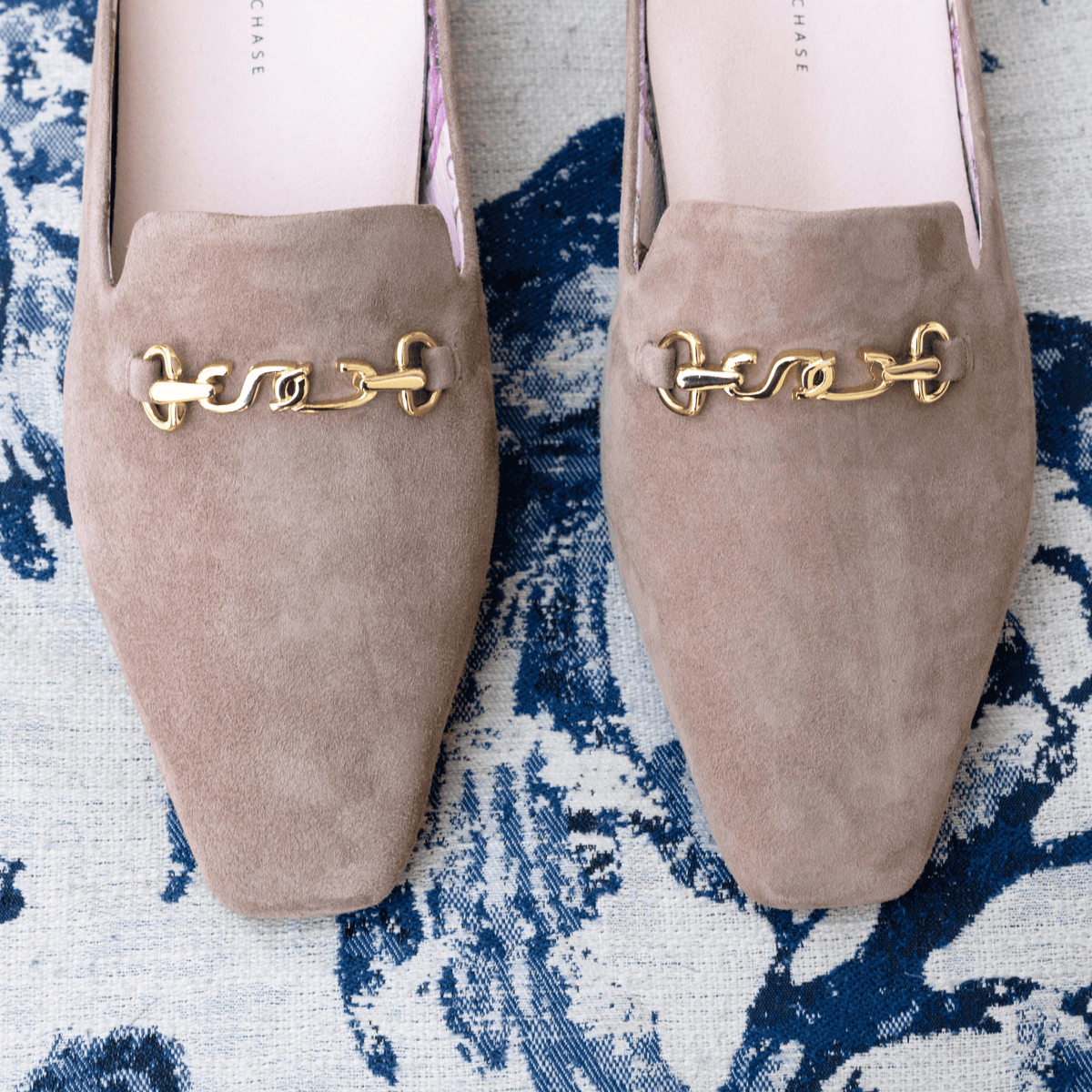 Scarlett Chase taupe suede Chase loafer with champagne SC accessory and floral lining| Overhead view of toe detail on blue and white print background