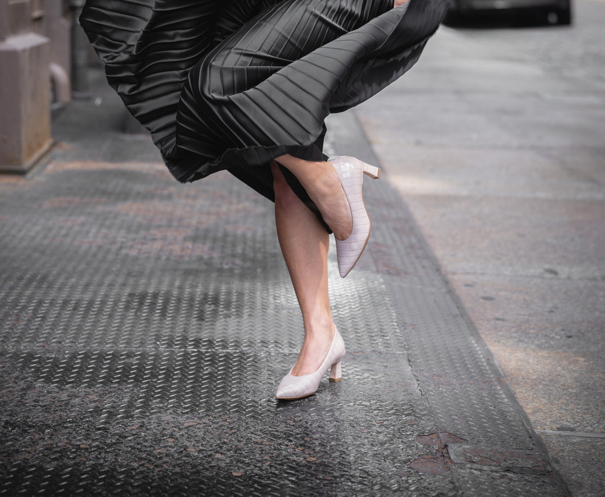 Scarlett Chase taupe embossed leather Amore 55 Pump with a rounded upper and block heel | 3/4 view on feet black skirt on model running on black street in city front foot on ground back leg bent and whole shoe off ground