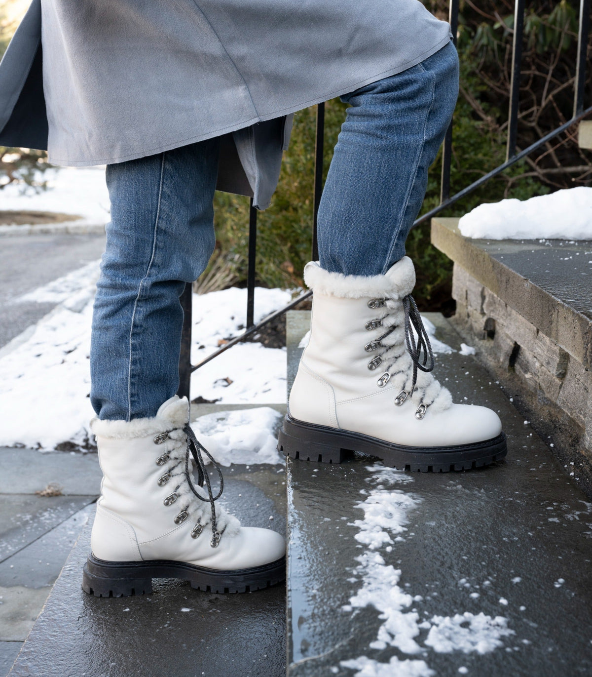 Person standing on snowy stairs outside wearing the Aspen Boot with white leather and black laces.