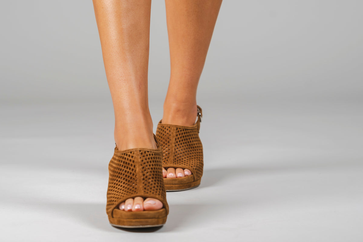 Scarlett Chase Chelsea Wedge Sandal with a perforated leather upper and adjustable back strap | Sienna Suede sandals on woman's staggered-standing feet on light gray background