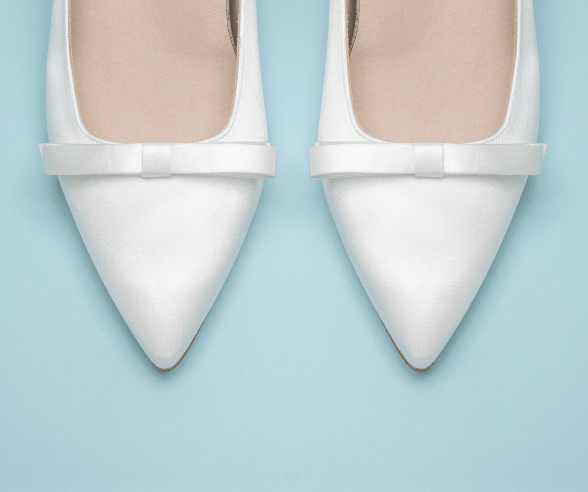 Scarlett Chase Gloria 55 White Satin Pump with a rounded upper, minimalist satin bow, and a sculpted heel | Overhead 3/4 view on light blue background