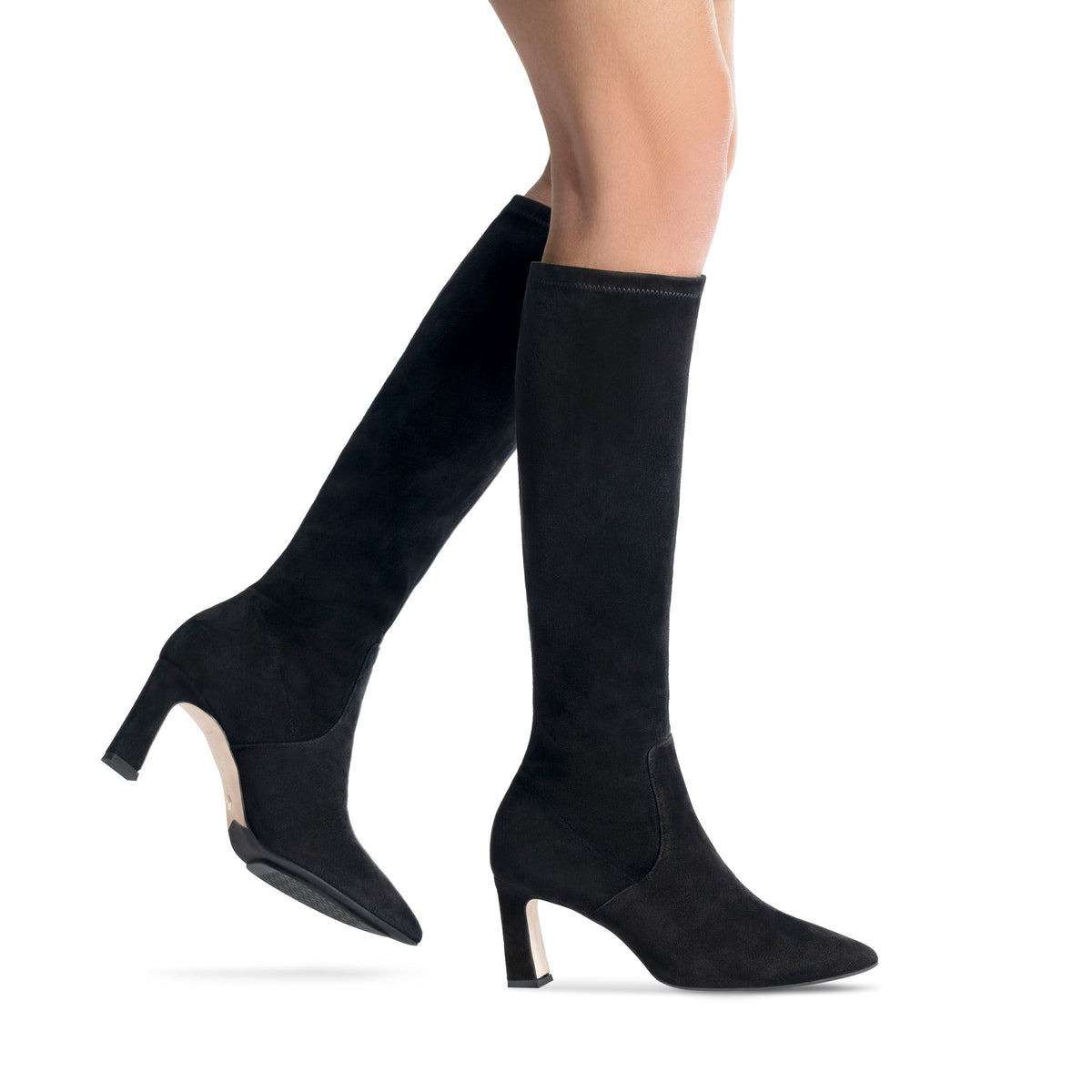 Scarlett Chase knee-high stretch black suede Lola 75 boot with a block heel | On model bare legs walking back leg off ground on white background