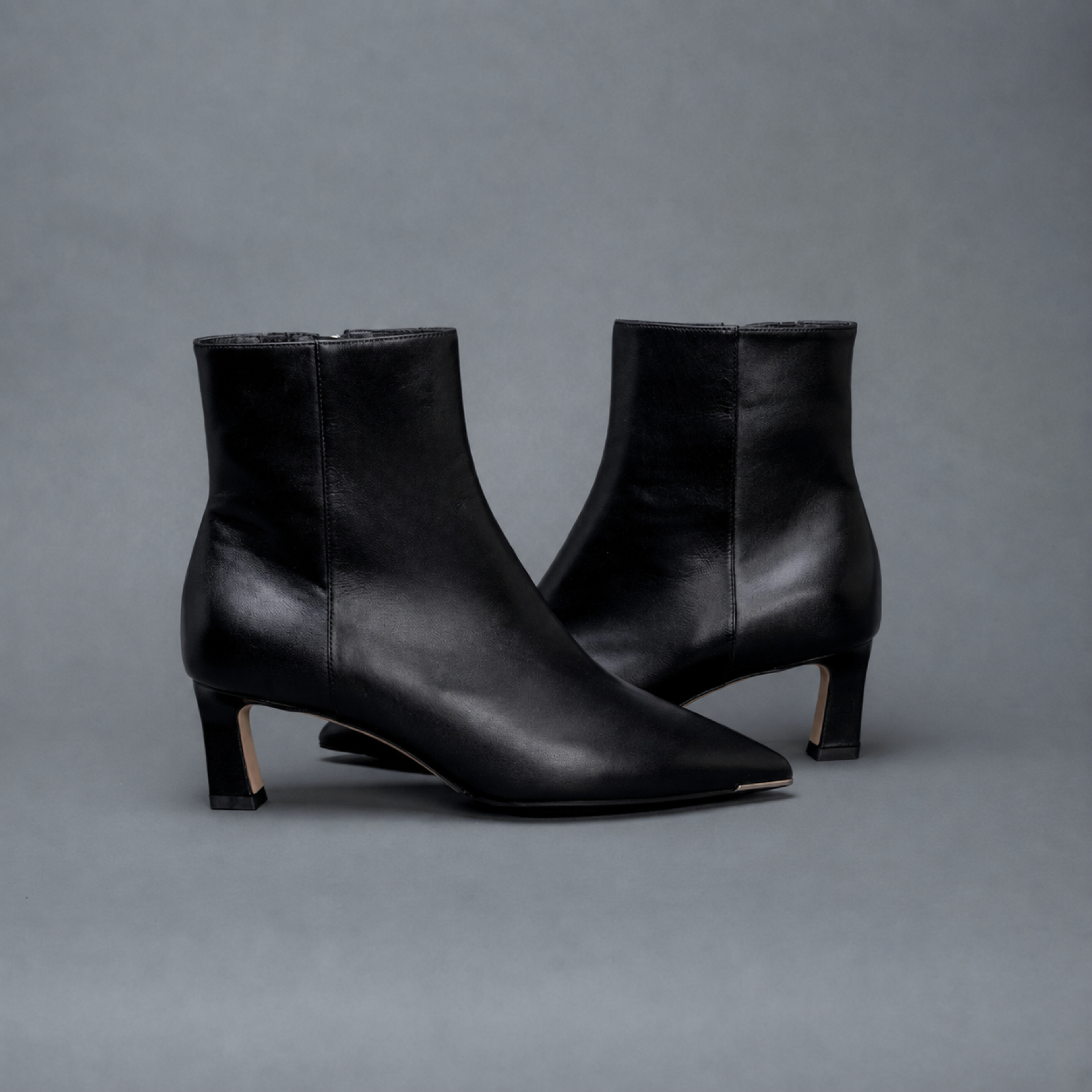 Scarlett Chase ankle zip black napa Aimee 55 bootie with a block heel and gore stretch | Side view of pair facing opposite directions on gray background