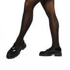 Scarlett Chase Ava Lug Penny Loafer in Black Leather with a lightweight sole and SC coin | Person wearing black tights wearing loafers on white background