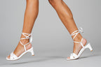Scarlett Chase Cali 45 white satin dress sandal with wrap-around ties and a gathered front | On foot of a model walking on a grey background