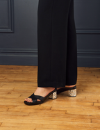 Scarlett Chase Carmel 45 contrast block heel sandal with a mesh-lined upper | black leather, person standing in black pants, 3/4 view, on wooden floor with blue walls