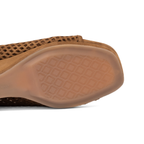 Scarlett Chase Chelsea Wedge Sandal with a perforated leather upper and adjustable back strap | Sienna Suede single sandal - Close-up of the outsole and side profile of a sandal, showing a textured geometric pattern on the rubber sole against a white background.