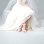 Scarlett Chase white satin Coco 45 dress sandal with minimalist straps and an adjustable backstrap | 3/4 view on seated bride on white background