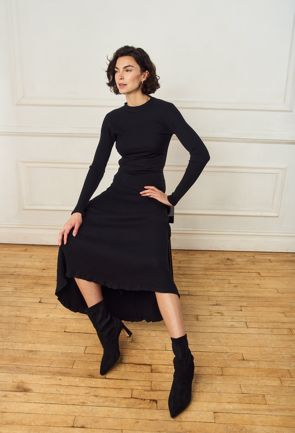Scarlett Chase ankle stretch black suede Portia 75 bootie with a block heel |3/4 view on model with long black dress on wooden floor and white background