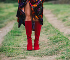 Scarlett Chase knee-high stretch red suede Lola 75 boot with a block heel | On model in dark colored velvet long dress on grass outside front view 