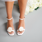 Scarlett Chase white satin Coco 45 dress sandal with minimalist straps and an adjustable backstrap and chantelle floret | Top down view on bride with floret on gray background with flowers 