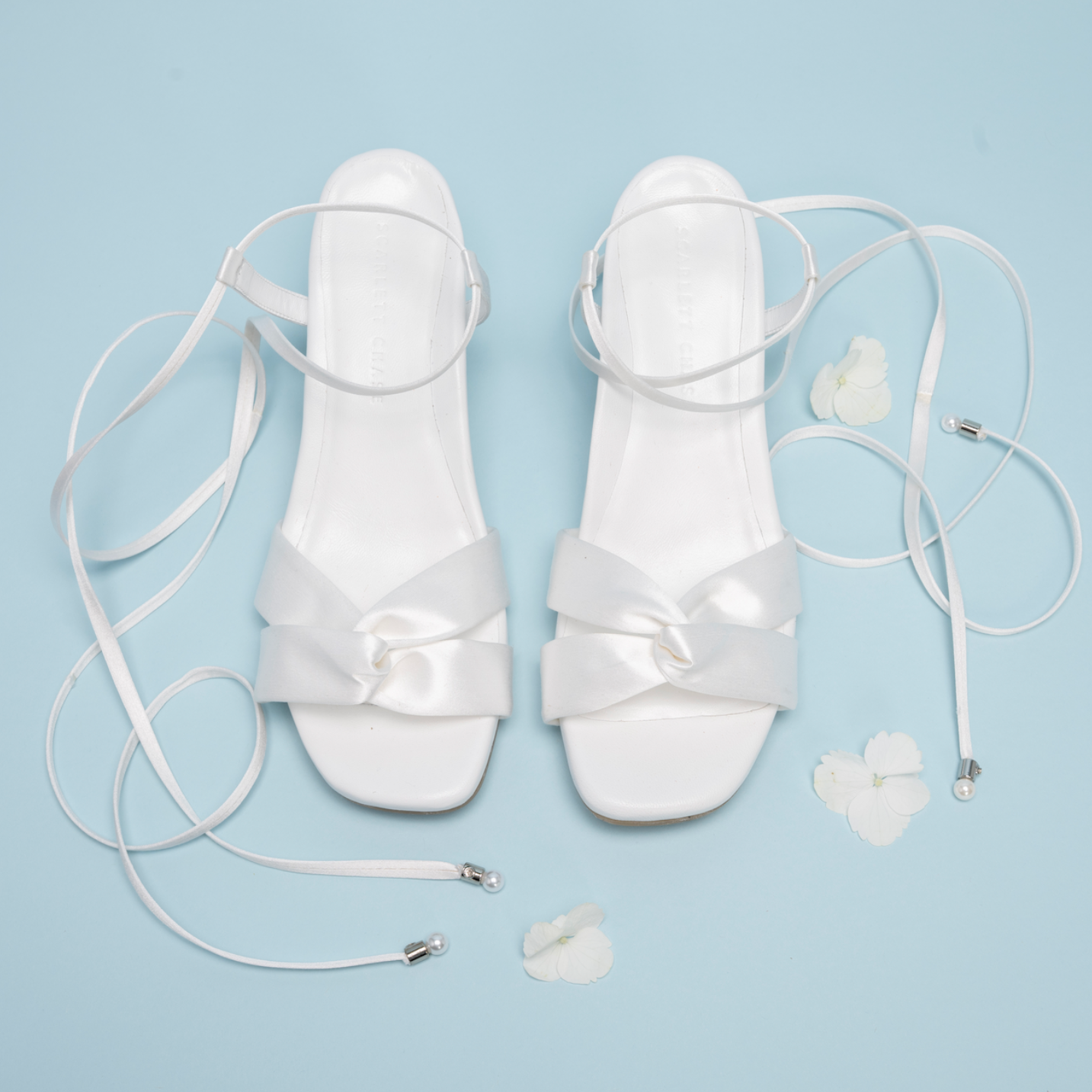 Scarlett Chase Cali 45 white satin dress sandal with wrap-around ties and a gathered front | Overhead view on blue background