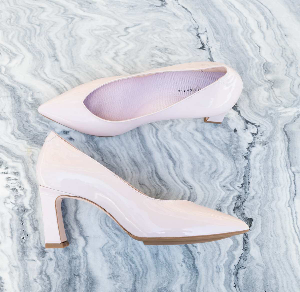Scarlett Chase Scarlett 75 Pump Light Pink Patent with a V-cut upper and block heel | Profile on one shoe and overhead view of the other on a marble white background