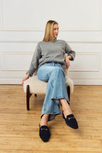 Scarlett Chase Weston Mule in Navy Suede with floral lining and an SC gold accessory | Lifestyle shot in jeans on feet with wood floor background