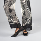 Scarlett Chase noir mesh upper with italian patent leather Brie Ballet with a 3/4 elastic contrast Mary Jane strap, leather contrast trim, and contrast toe cap | On feet models legs visible with printed pant left shoe sideways with heel in air, right show facing forward on white background