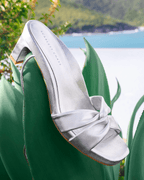 Scarlett Chase silver metallic nap leather Cali 45 dress sandal with wrap-around ties and a gathered front | 3/4 view on leaves in a beach setting outside