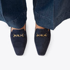 Scarlett Chase navy suede Chase loafer with champagne SC accessory and floral lining | overhead view on feet with navy pants and a white background