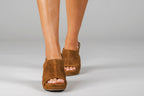 Scarlett Chase Chelsea Wedge Sandal with a perforated leather upper and adjustable back strap | Sienna Suede sandals on woman's staggered-standing feet on light gray background