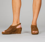 Scarlett Chase Chelsea Wedge Sandal with a perforated leather upper and adjustable back strap | Sienna Suede Sandal worn by person pointing one foot to the side and one foot facing front on a light gray background