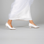 Scarlett Chase Gloria 55 White Satin Pump with a rounded upper, minimalist satin bow, and a sculpted heel | On model feet on grey background 