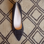 Scarlett Chase chocolate suede Greta 55 Pump with a rounded upper, sculpted heel, and chocolate toe accessory | Top down view of single shoe on cream and brown carpet in room 