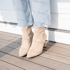Scarlett Chase ankle stretch champagne suede Maya 55 bootie with a block heel |On model with jeans on deck and white backdrop 3/4 view 