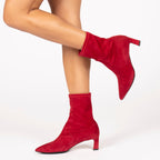 Scarlett Chase ankle stretch cosmo suede Maya 55 bootie with a block heel | On model bare legs one leg bent and in air side view of both on white background
