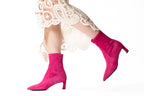 Scarlett Chase ankle stretch bright pink suede Maya 55 bootie with a block heel  |  On model white lace long dress walking back leg in air side view on white background