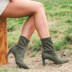 Scarlett Chase ankle stretch moss suede Portia 75 bootie with a block heel | On model outside on dirt and grass staggered side view with back heel in air and toe on ground