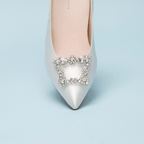 Roma 55 Scarlett Chase white Roma 55 Slingback with a stable, sculpted heel and an adjustable backstrap buckle and SC accessory | Overhead 3/4 view on sky blue background 