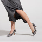 Scarlett Chase Soiree 75 Pump Gray Python with a V-cut upper and sculpted heel | Model wearing the shoes while shifting back and forth and pointed one toe on a light grey background