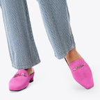 Scarlett Chase Weston Mule in Bright Pink Suede and an SC silver accessory | On feet on white background