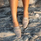 Scarlett Chase Weston Mule in Taupe Napa with floral lining and an SC gold accessory | Overhead view on feet on rock background