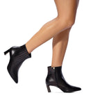 Scarlett Chase ankle zip italian black napa and calf leather Amelia 55  Bootie with a block heel and gore stretch | Side view on feet bare legs walking back leg in air on white background