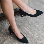 Scarlett Chase navy italian suede Amore 55 Pump Narrow Fit with a rounded upper and block heel | On feet sitting in chair one leg in air and profile other on floor 3/4 view on grey carpet